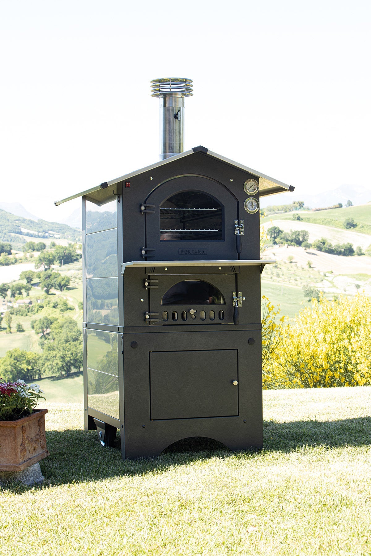 Fontana Gusto dual-chamber wood-fired oven shown on its cart outdoors; the image does not identify the selected size.